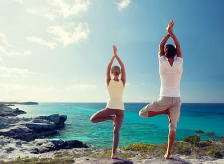 fitness, sport, and lifestyle concept - couple making yoga exercises on beach from back