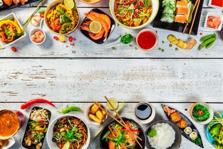 Asian food served on white wooden table, top view, space for text. Chinese and vietnamese cuisine set.